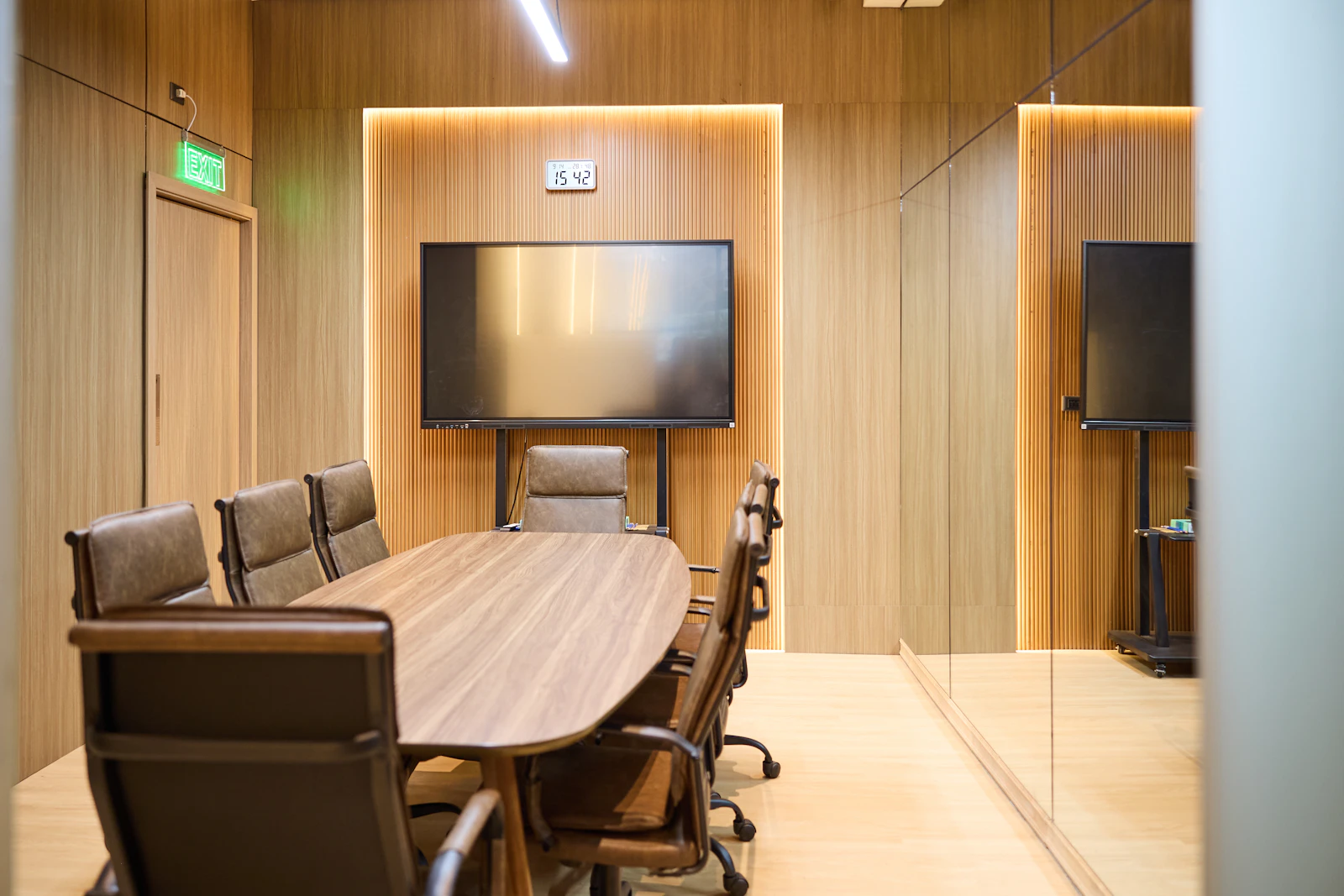 The firm's meeting room, with an oval timber table, leather chairs and a fluted timber wall lit from above