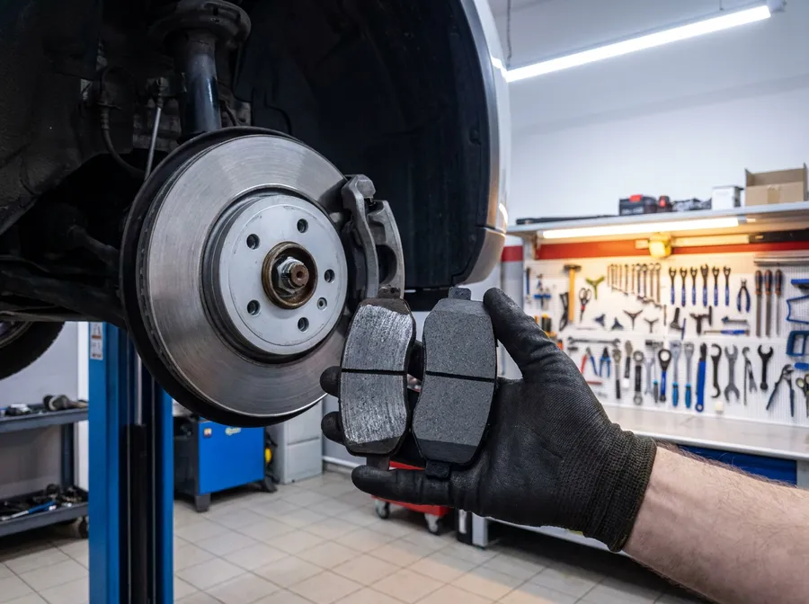 Photo sent with the message: a worn brake pad held next to a new one, beside the brake disc