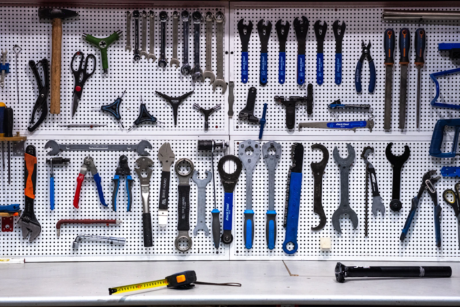Spanners, pliers and hand tools hung on a pegboard above a workbench